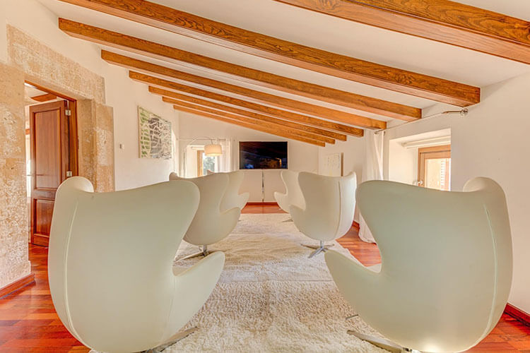 Stylish loft lounge with modern egg chairs and exposed wooden beams.