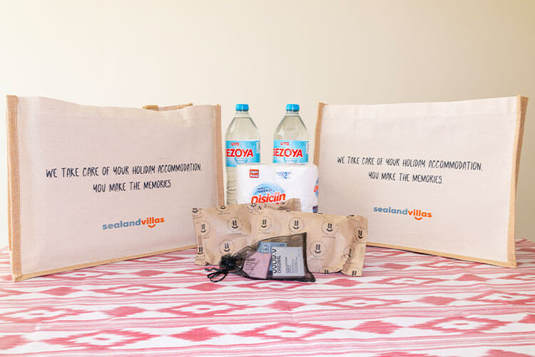 Essential welcome pack including bottled water, cleaning products, toiletries, and branded tote bags